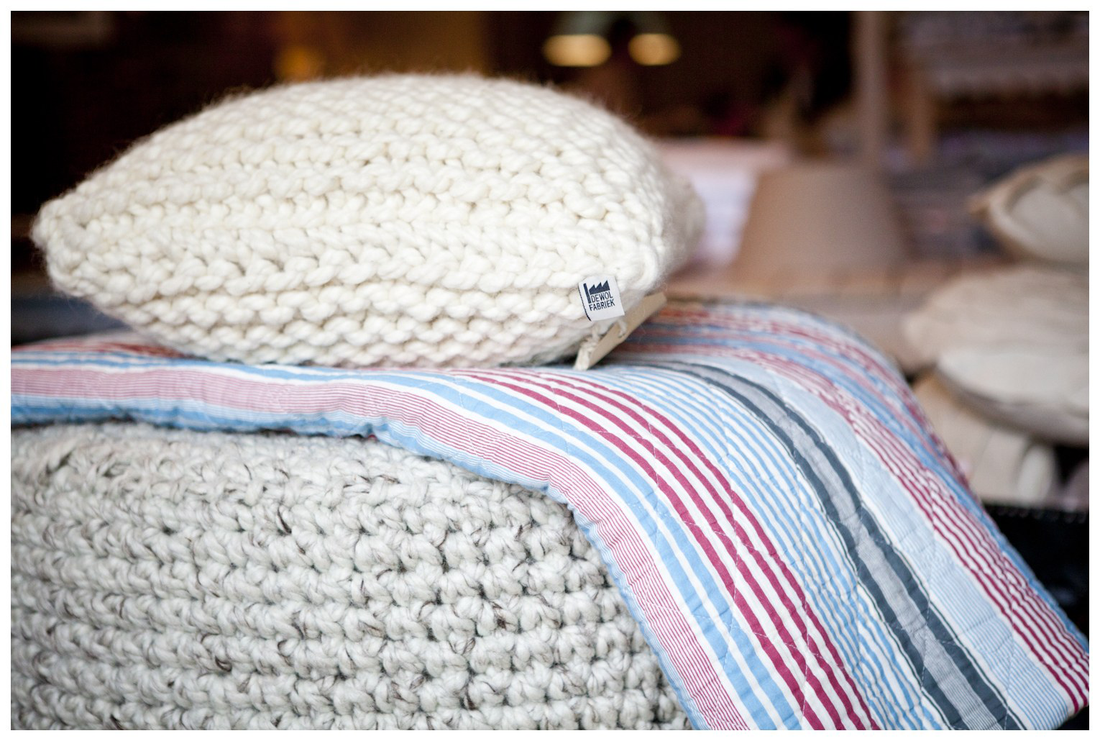 Lekker wollig: een gebreide sierkussen van schapenwol op een gebreide poef.