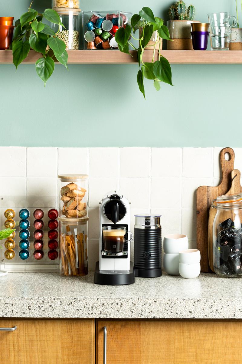 Witte Nespresso Original koffiemachine met bijbehorende accessoires.