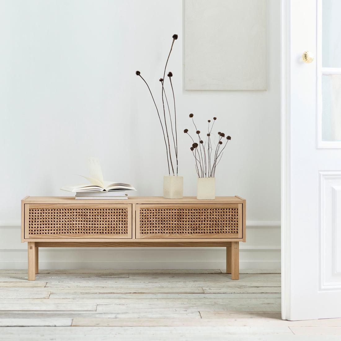 Bekijk de kast Het lage tv-meubel van rotan kan ook dienstdoen als plek om mooie bloemen neer te zetten en een stapeltje boeken of tijdschriften op te leggen.