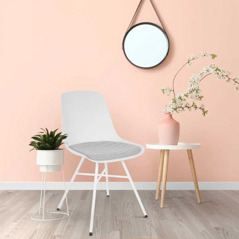 Bekijk deze stoel Een gekleurde muur, een witte eetkamerstoel. Plaats voor het comfort een grijs zitkussen bij de stoel, en het plaatje is compleet.
