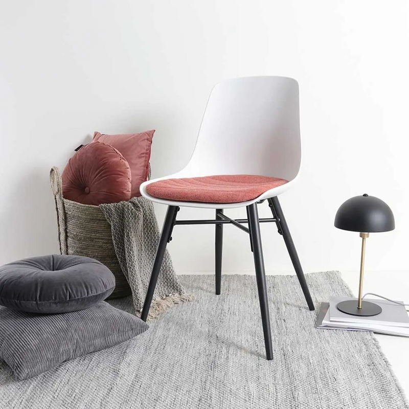 Bekijk deze stoel Een zachtroze zitkussen past goed bij zwart en bij wit. En zorgt voor een warm contrast bij de witte eetkamerstoelen.